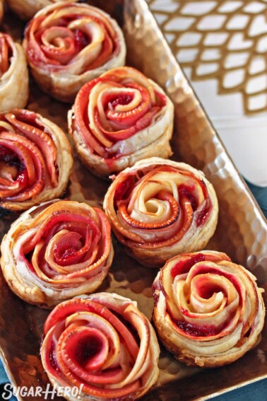 Baked Puff Pastry Apple Roses on a baking tray on a teal napkin.