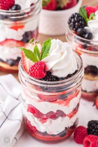 Mixed berry shortcake in a jar with berries, whipped cream, and shortcakes.
