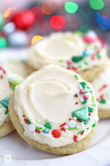 Close-up of a big round sugar cookie with vanilla sugar cookie frosting and colorful Christmas sprinkles on top.