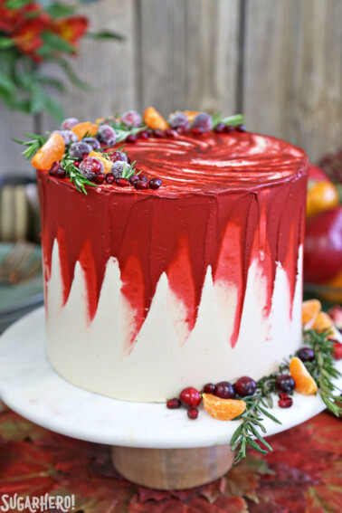Brown Sugar Cranberry Cake on a white cake platter with fruit in the background.