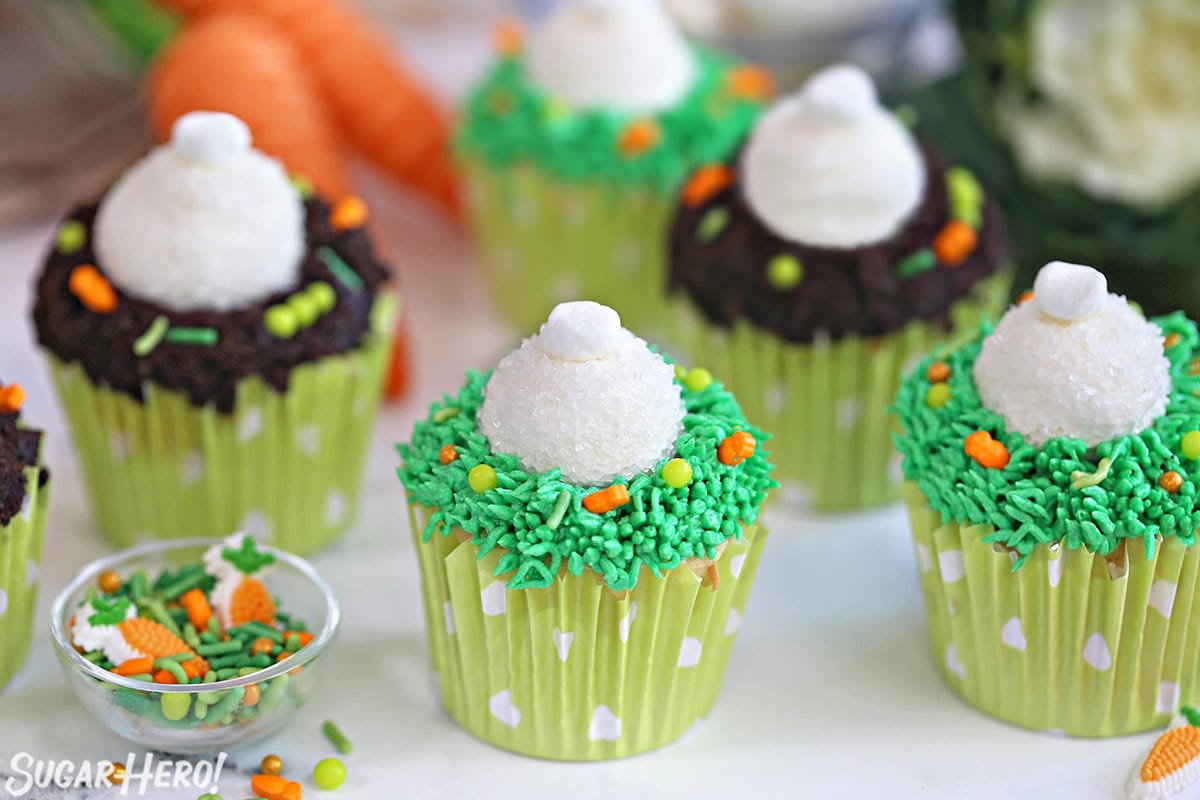 Several Bunny Butt Cupcakes on a white counter top next to a small bowl of Easter candies.