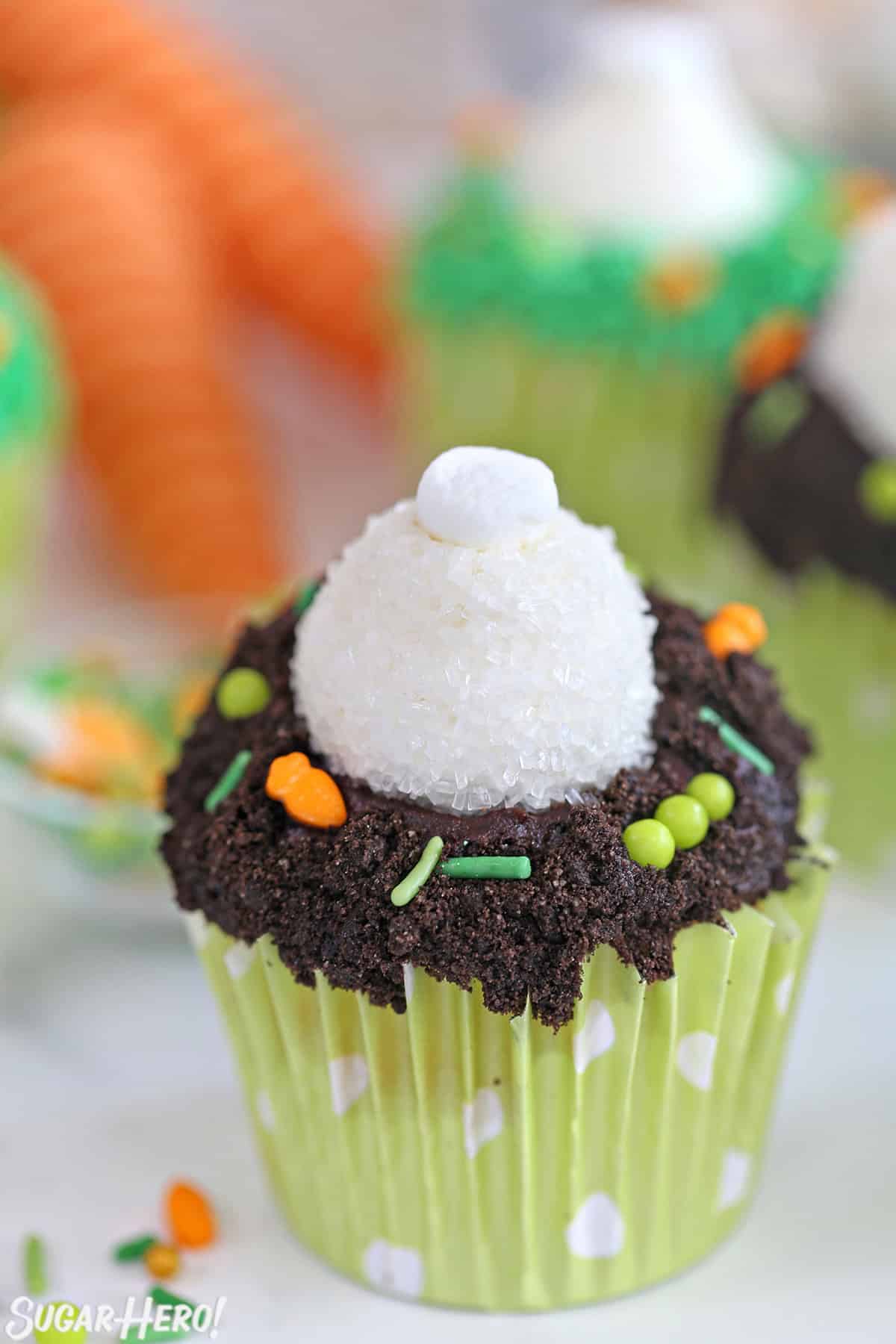 Close up of a Bunny Butt Cupcake with Easter veggie sprinkles scattered around.
