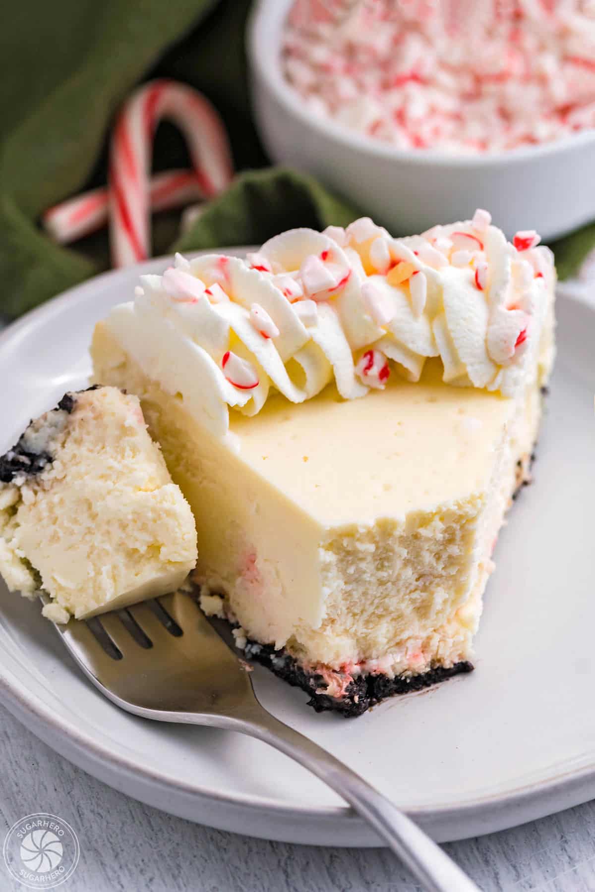 Slice of Candy Cane Cheesecake on a white plate, with a bite taken out of it.