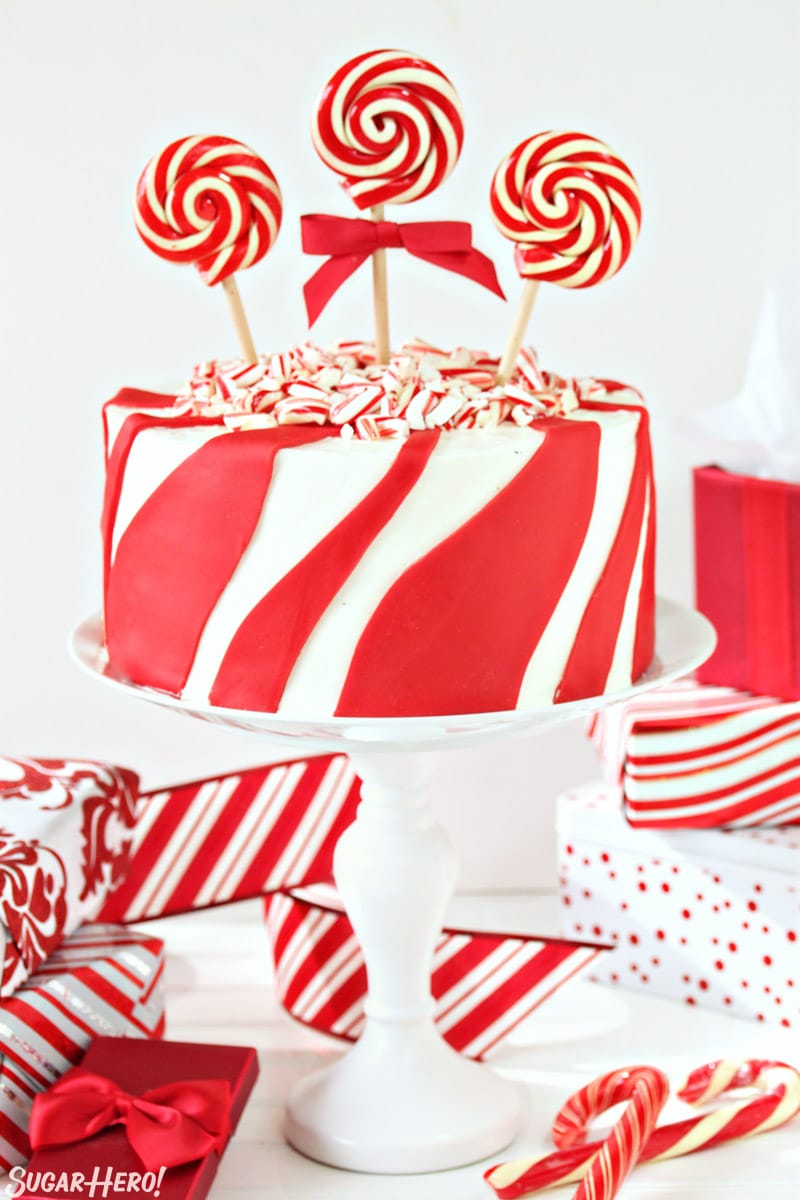 Candy Cane Chocolate Cake - vertical image of cake on cake stand with wrapped presents around | From SugarHero.com