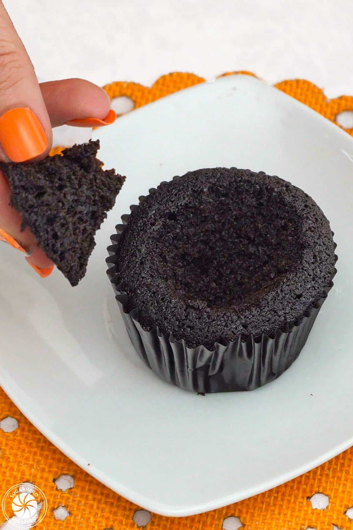 Removing a cone of chocolate cake cut out from a cupcake.