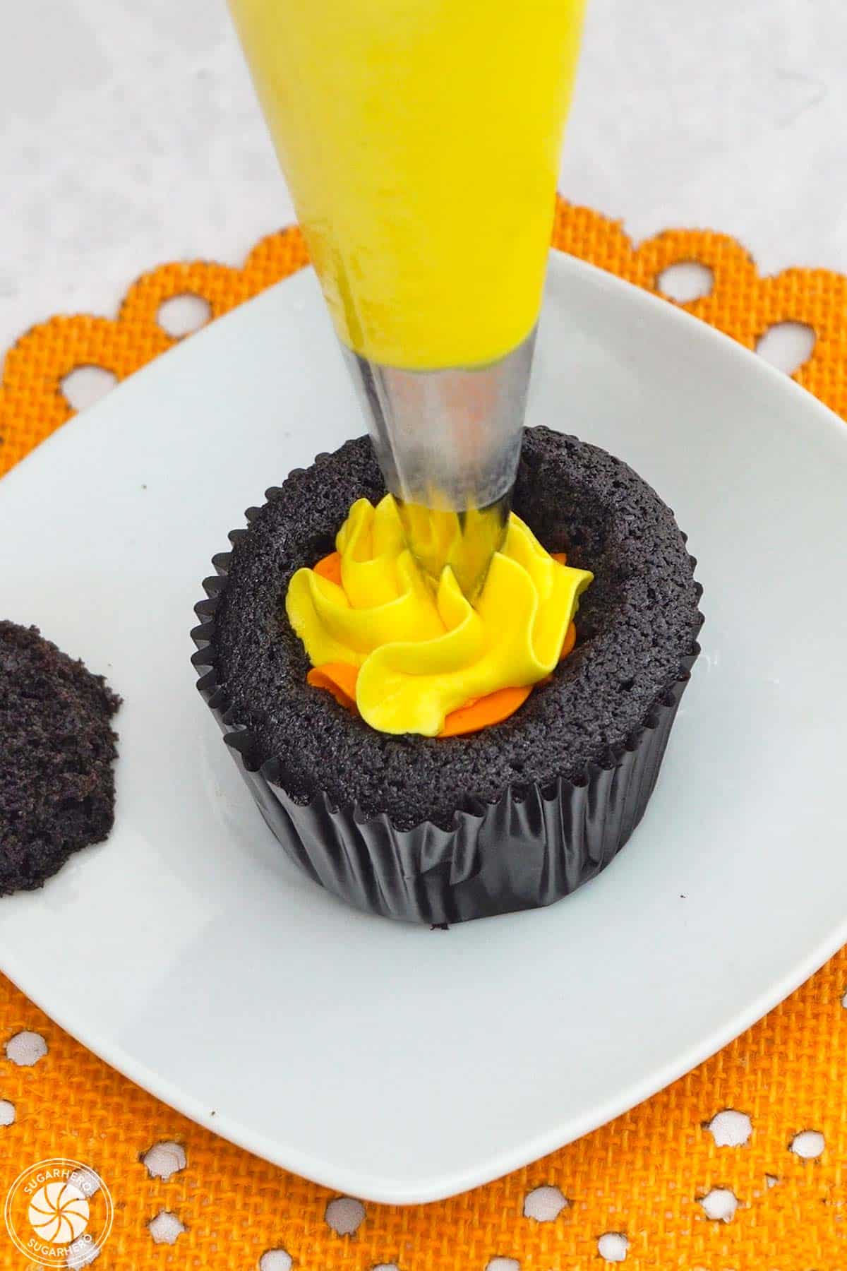 Piping yellow buttercream into the center of a Piping orange buttercream on a Candy Corn Cupcake.