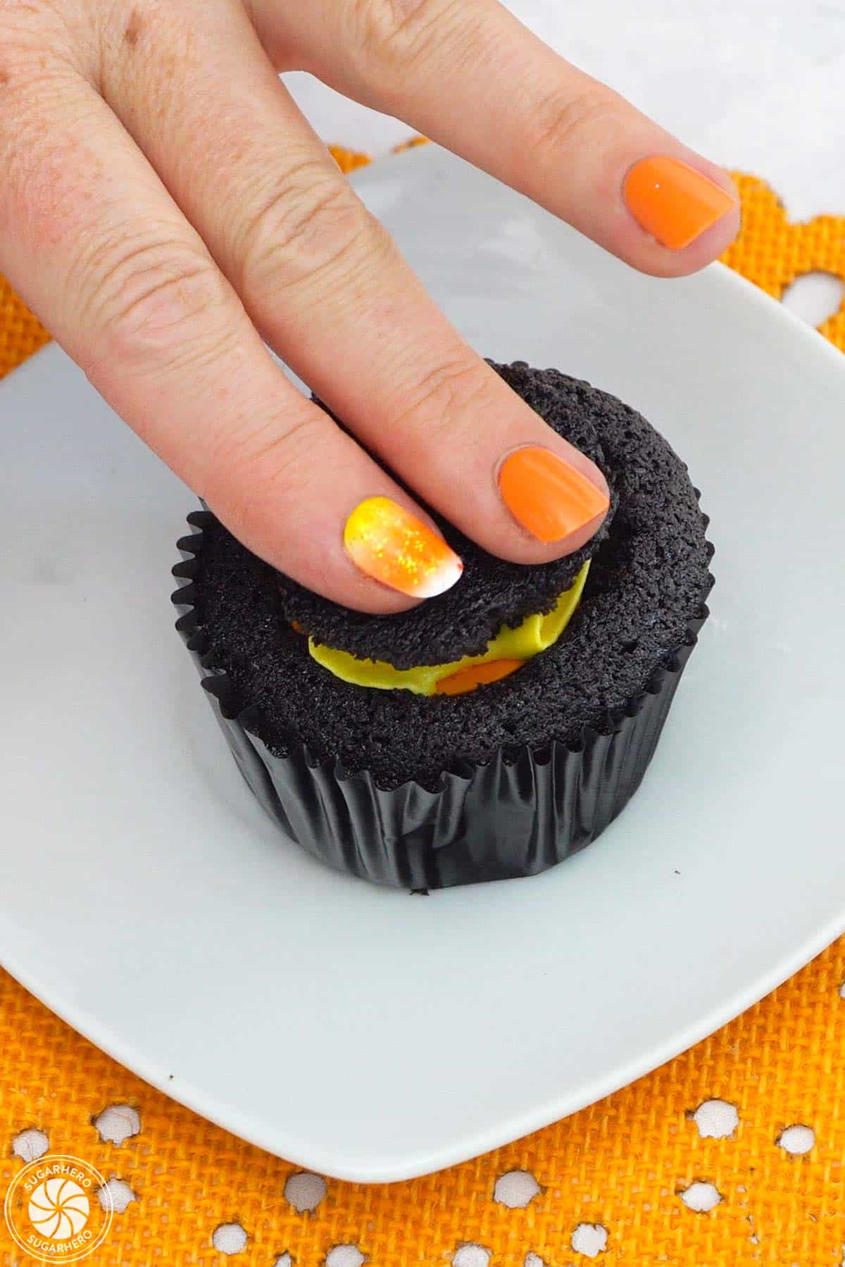 Pressing the top of the filled chocolate cupcake down.