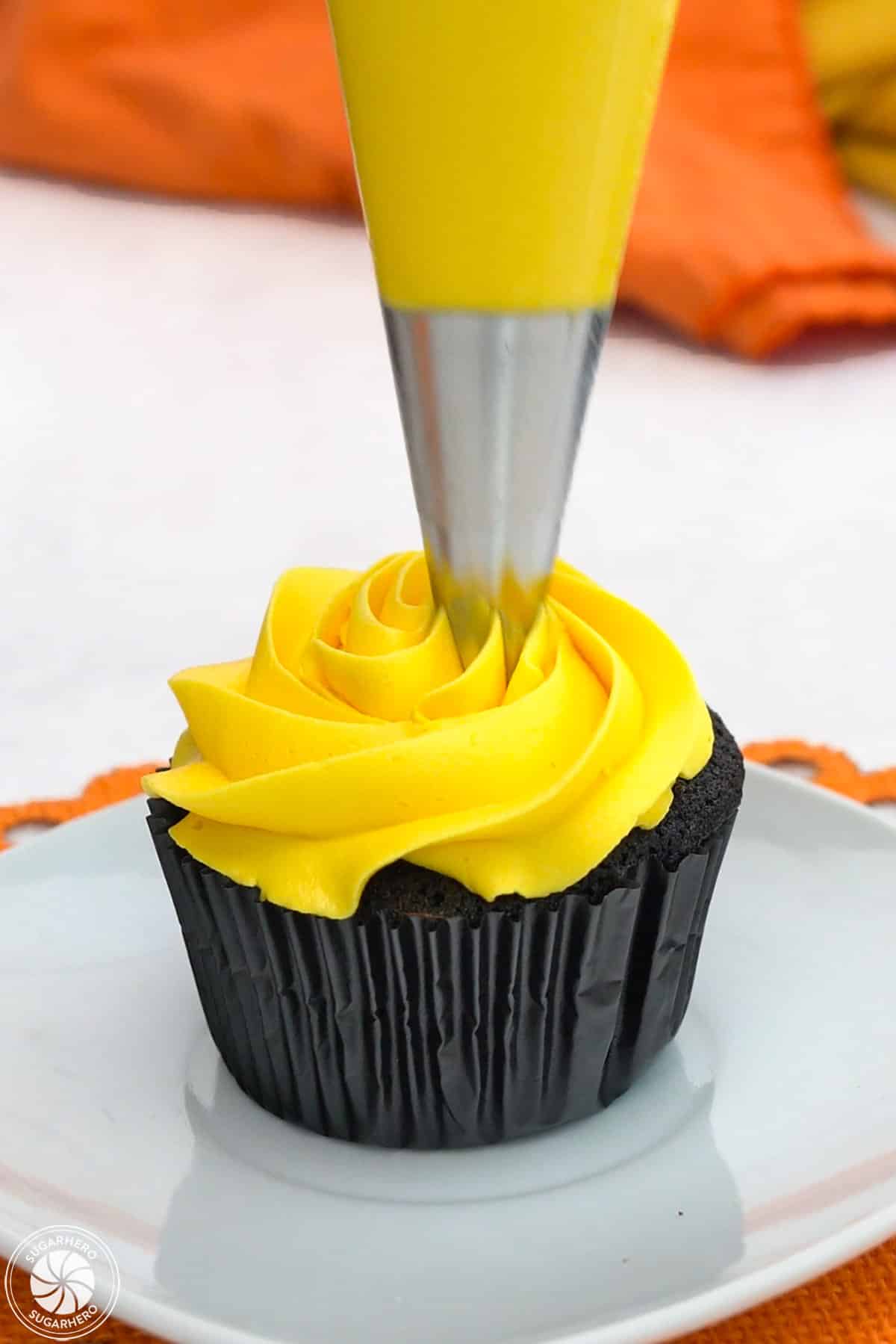 Piping yellow buttercream on a Candy Corn Cupcake.