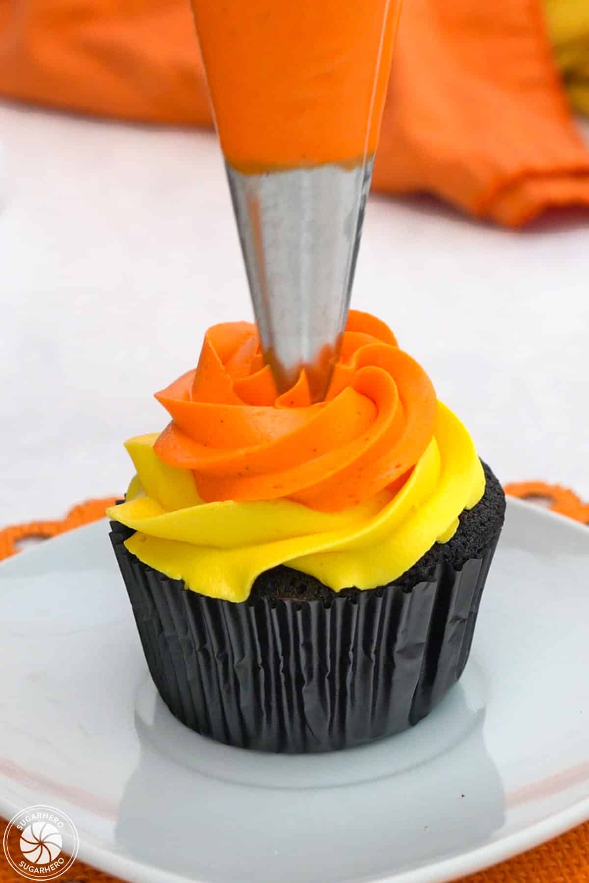Piping orange buttercream on a Candy Corn Cupcake.