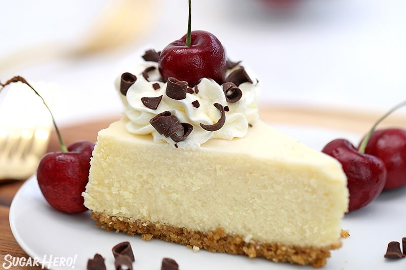 Slice of cheesecake with fresh cherries and chocolate curls on top.