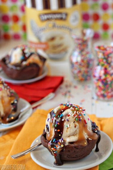 A chocolate cookie cup on a small white plate filled with ice cream and toppings.