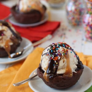 Close up of a scoop of ice cream in a Chocolate Cookie Ice Cream Cup with sauce and sprinkles on top.