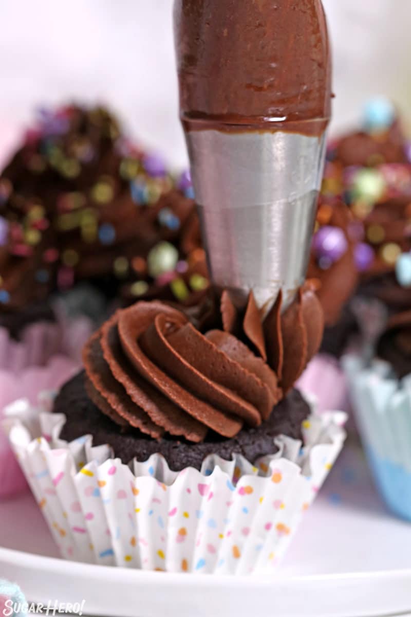 Homemade chocolate cupcakes with chocolate frosting being piped on top