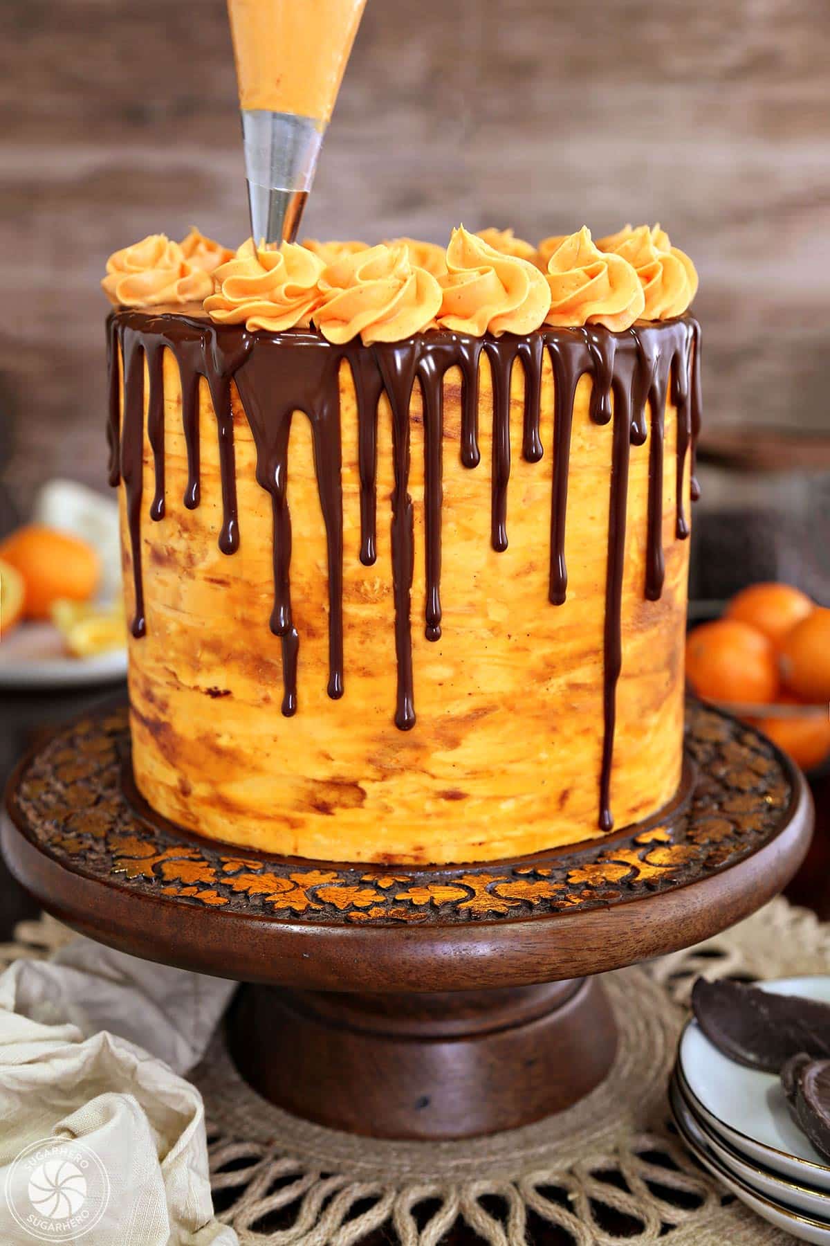 Placing a ring of orange buttercream swirls around the outside of a chocolate orange cake.