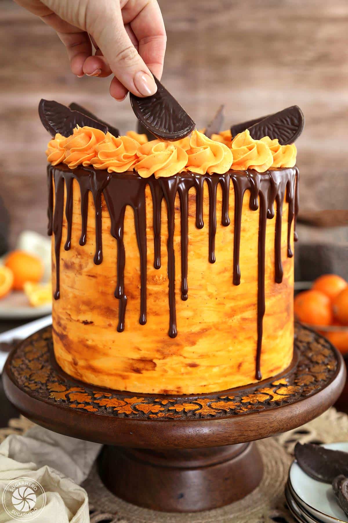 Placing chocolate orange slices as garnishes on the top of a chocolate orange cake.