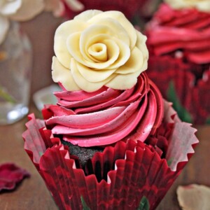 A chocolate cupcake with swirled frosting and a white chocolate rose on top.
