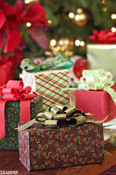 4 Chocolate-Wrapped Present Cakes in front of a Christmas decor.