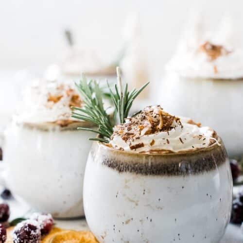 Side view of a mug of Coconut Milk Hot Chocolate next to sugared cranberries and orange slices.