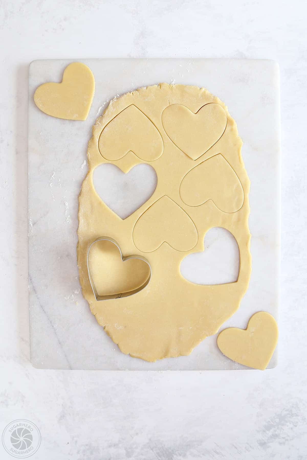 Rolled sugar cookie dough with hearts cut out of it.
