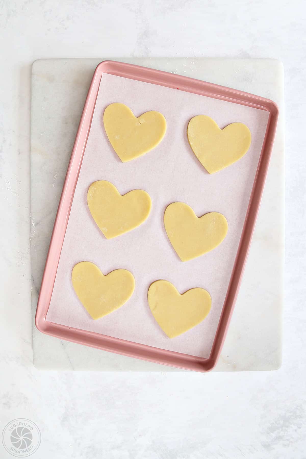 Heart shaped cookie dough on a bake sheet.