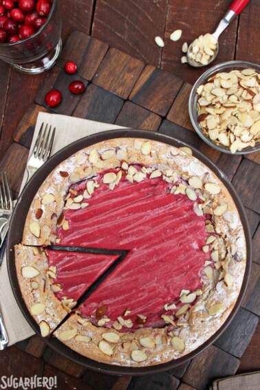 Cranberry Curd Almond Cake on a brown plate with a slice being removed.