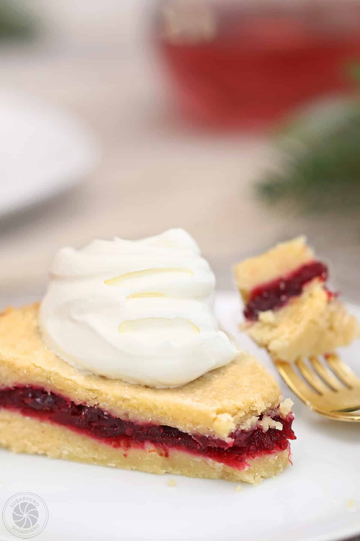Slice of Cranberry Sauce Cake on a white plate, with a bite taken out by a gold fork.