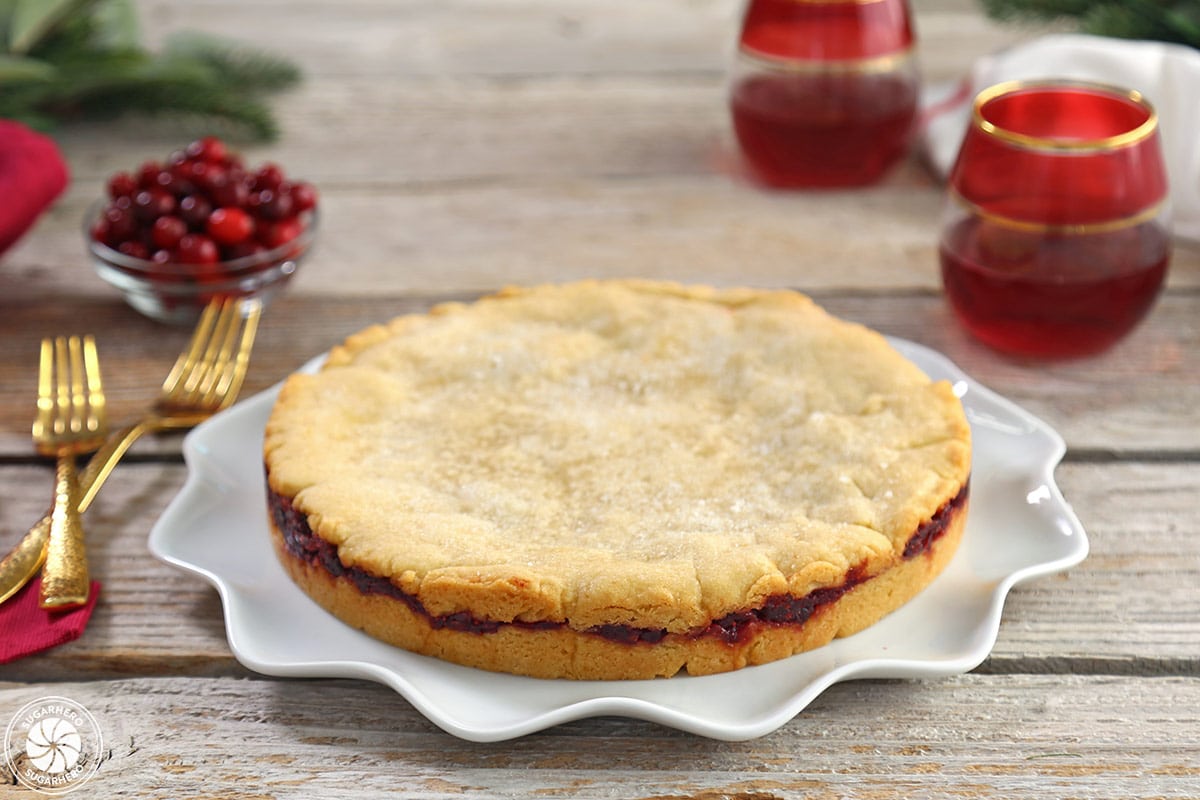 Whole Cranberry Sauce Cake on a fluted white plate, on rustic wooden planks.