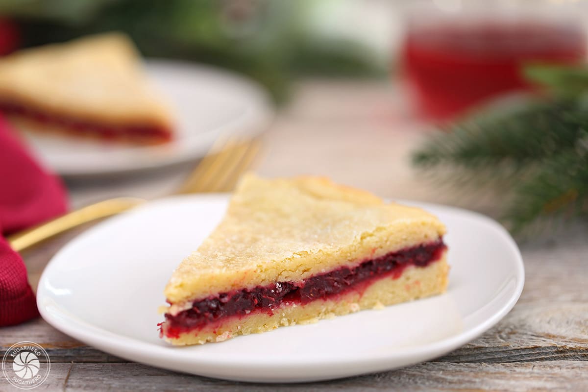 Slice of Cranberry Sauce Cake on a white plate, with a gold fork in the background.