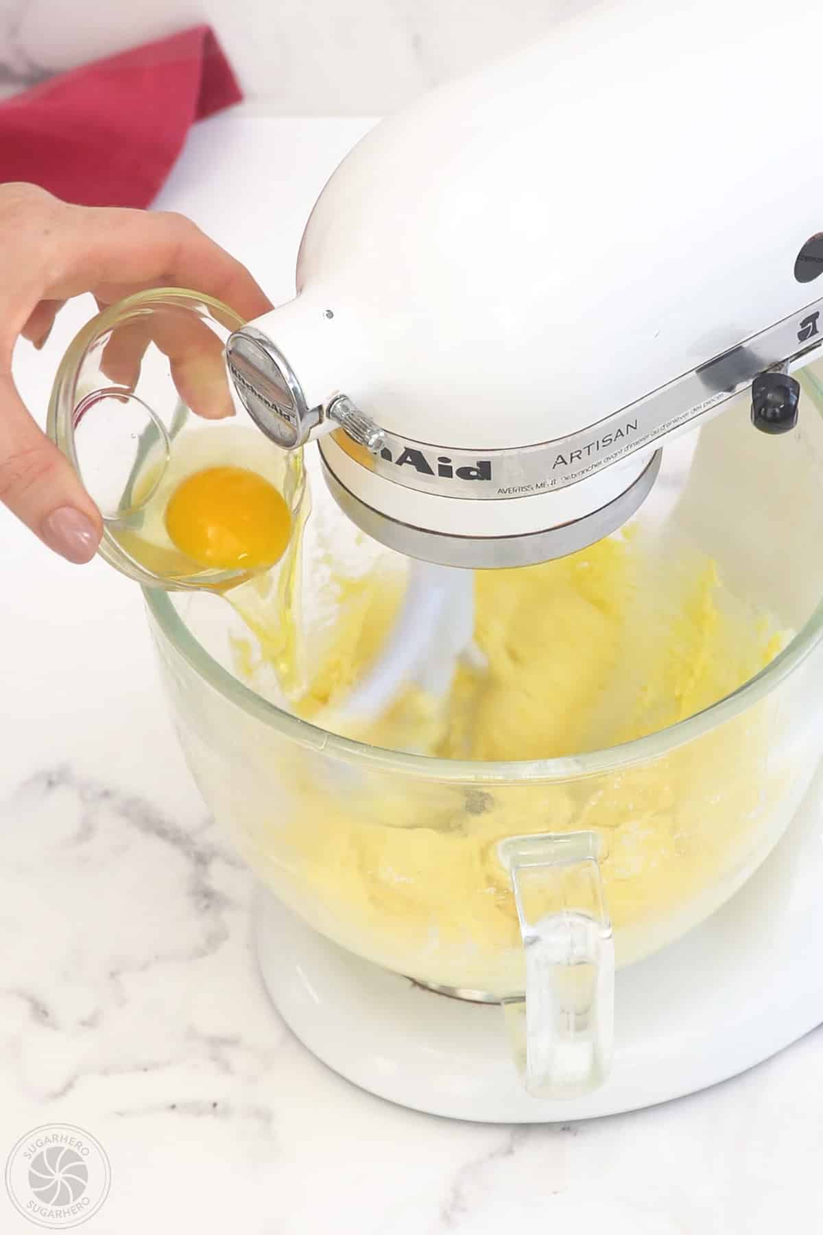 Adding an egg to creamed mixture.