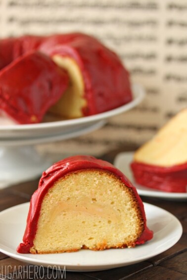 Slice of Cream Cheese Cake with Red Velvet Fudge Frosting on a white plate.