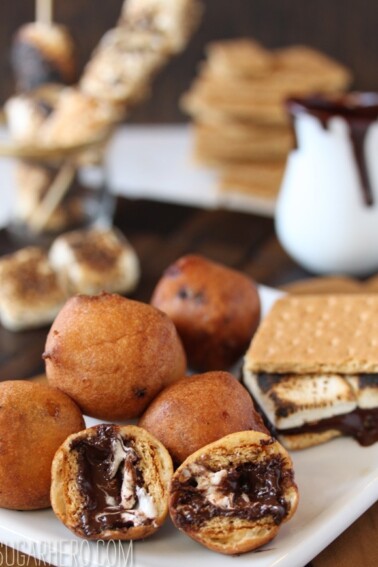 A pile of Deep Fried S'mores on a serving plate with the front ball cut in half to show interior.