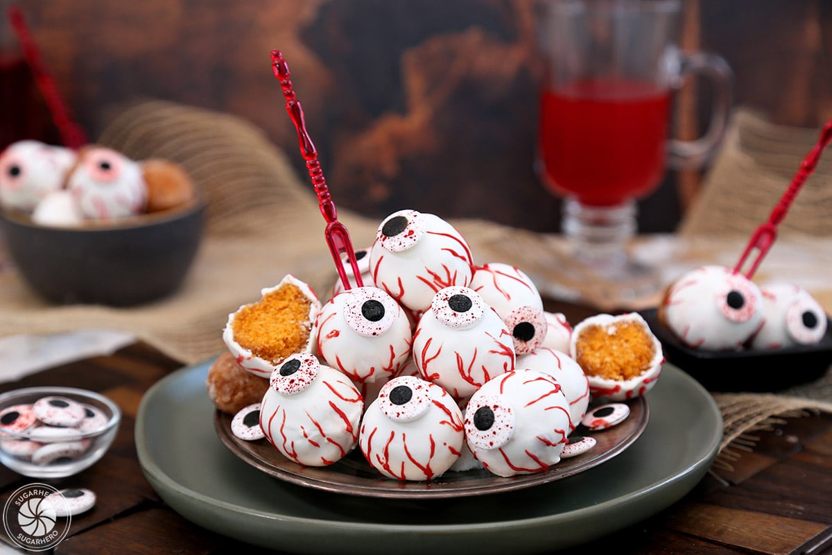 Plate of Donut Hole Eyeballs with red appetizer forks sticking out of some of them.