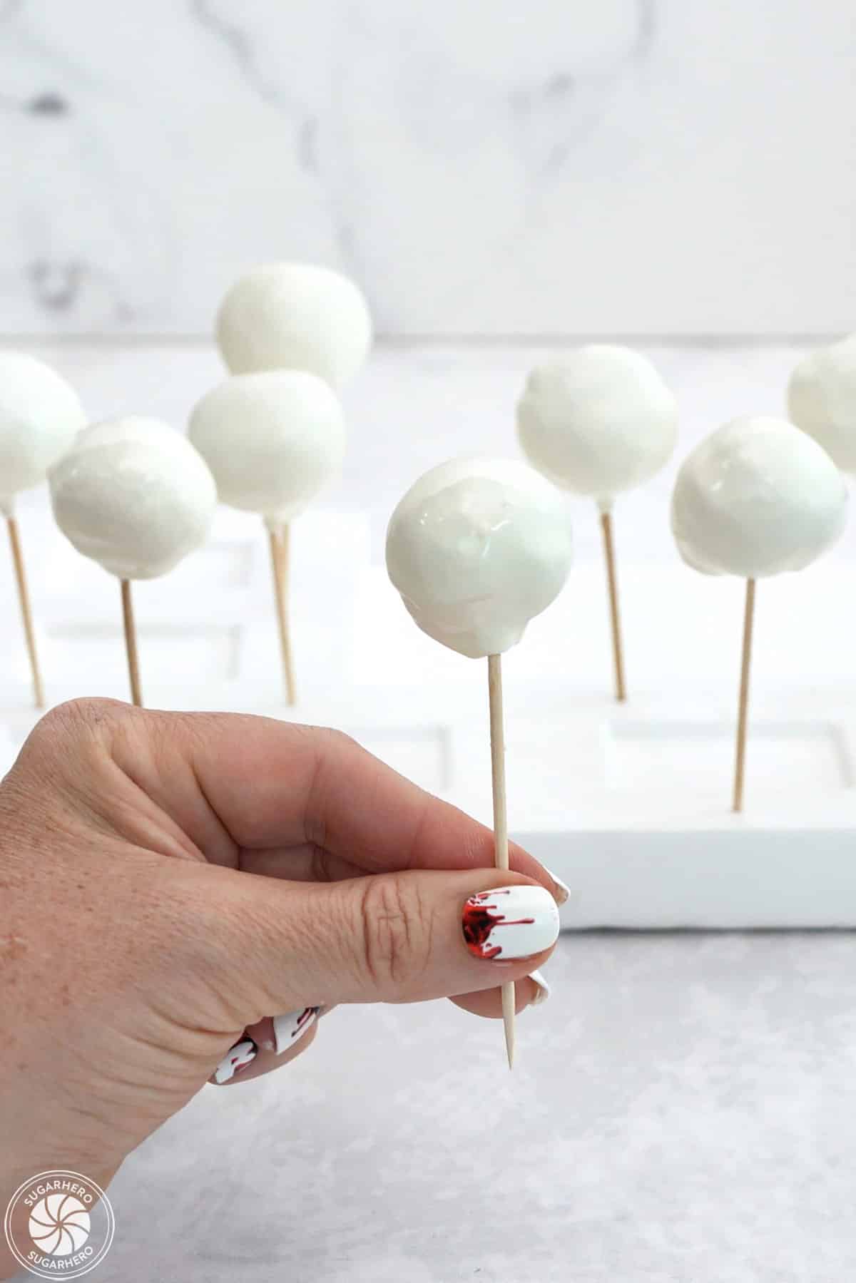 Hand placing dipped donut holes into styrofoam.