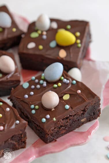 Easter Egg Brownies on a pink plate with pastel sprinkles and chocolate eggs on top.