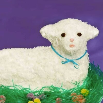 Lamb cake covered in flaked coconut against a purple background.