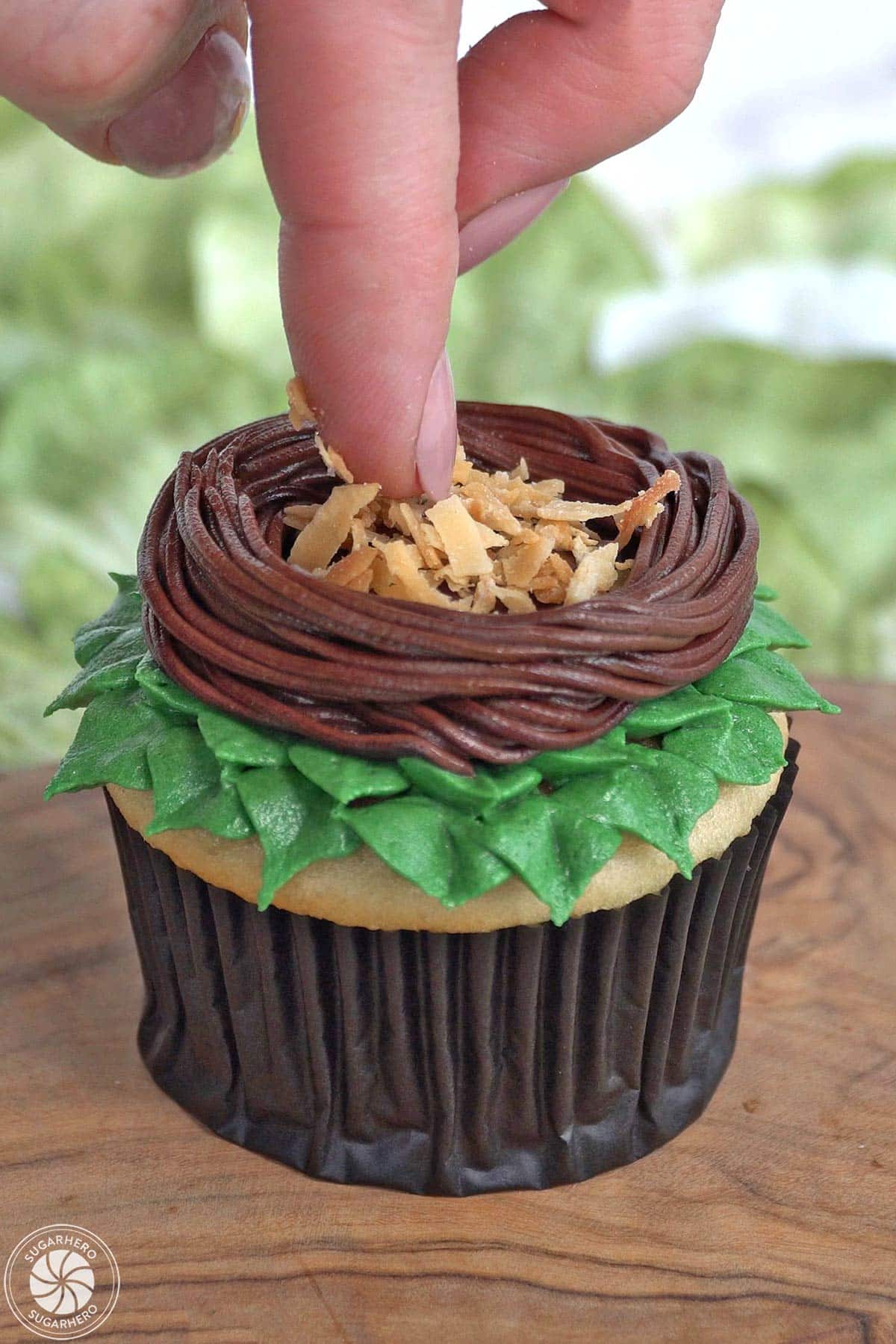 Pressing toasted coconut into the center of a buttercream nest.