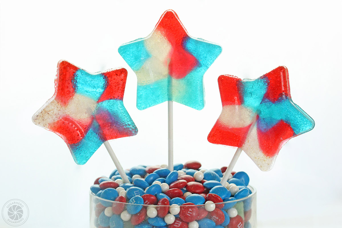 Easy Homemade Lollipops - three red, white, and blue translucent lollipops | From SugarHero.com