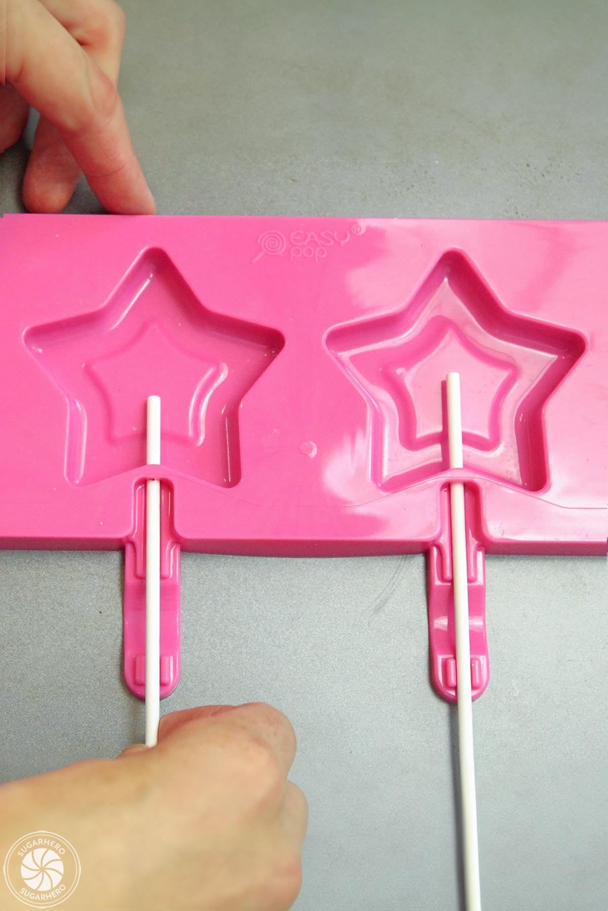 Hand inserting lollipop sticks in a silicone star mold.
