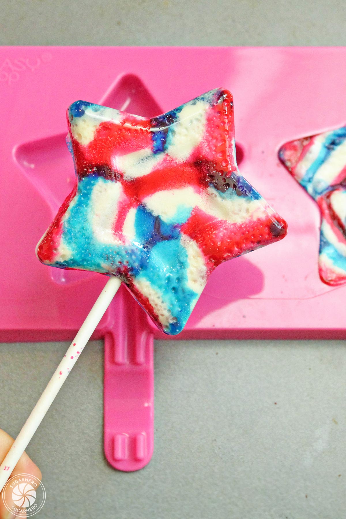Hand holding up a star-shaped lollipop.