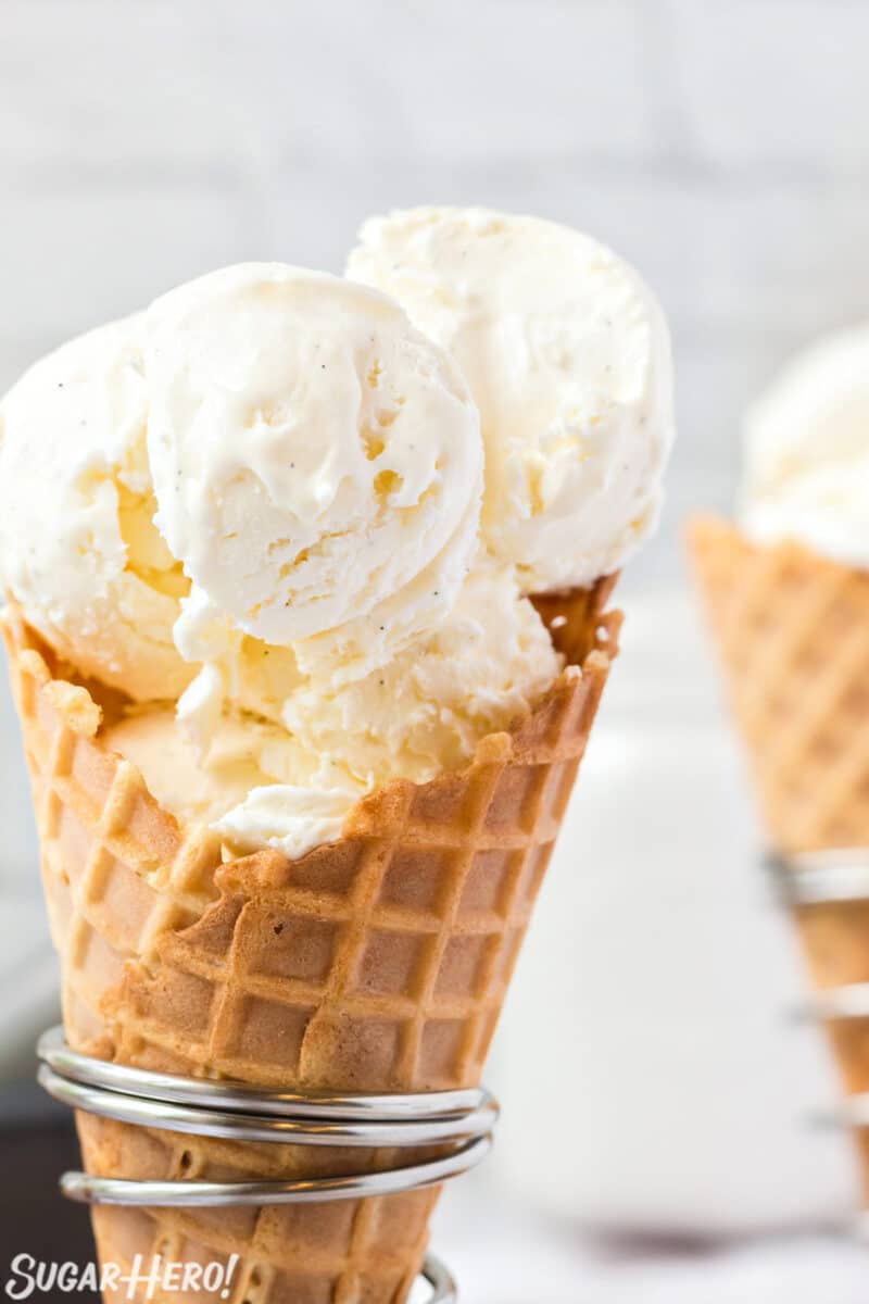 Close-up of waffle cone holding big scoops of vanilla bean ice cream.