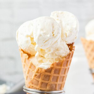 Close-up of waffle cone holding big scoops of vanilla bean ice cream.