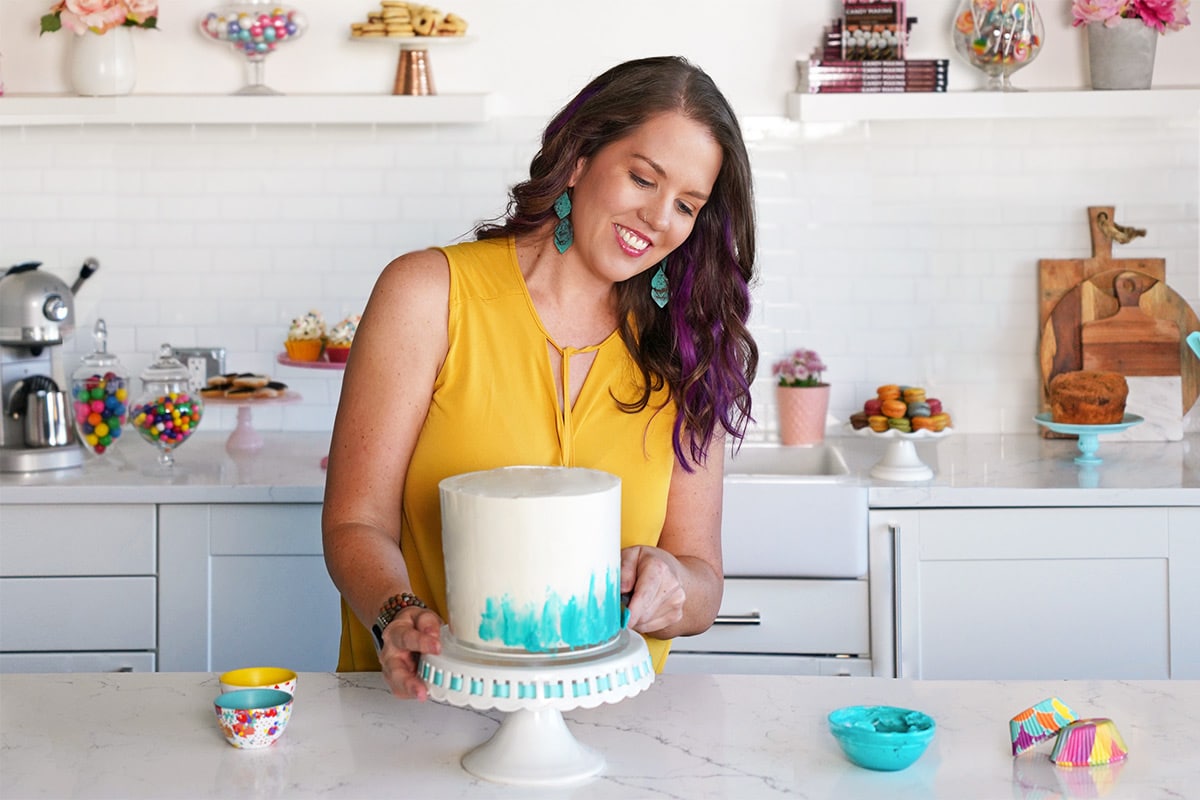 Elizabeth LaBau in a yellow shirt decorating a cake.