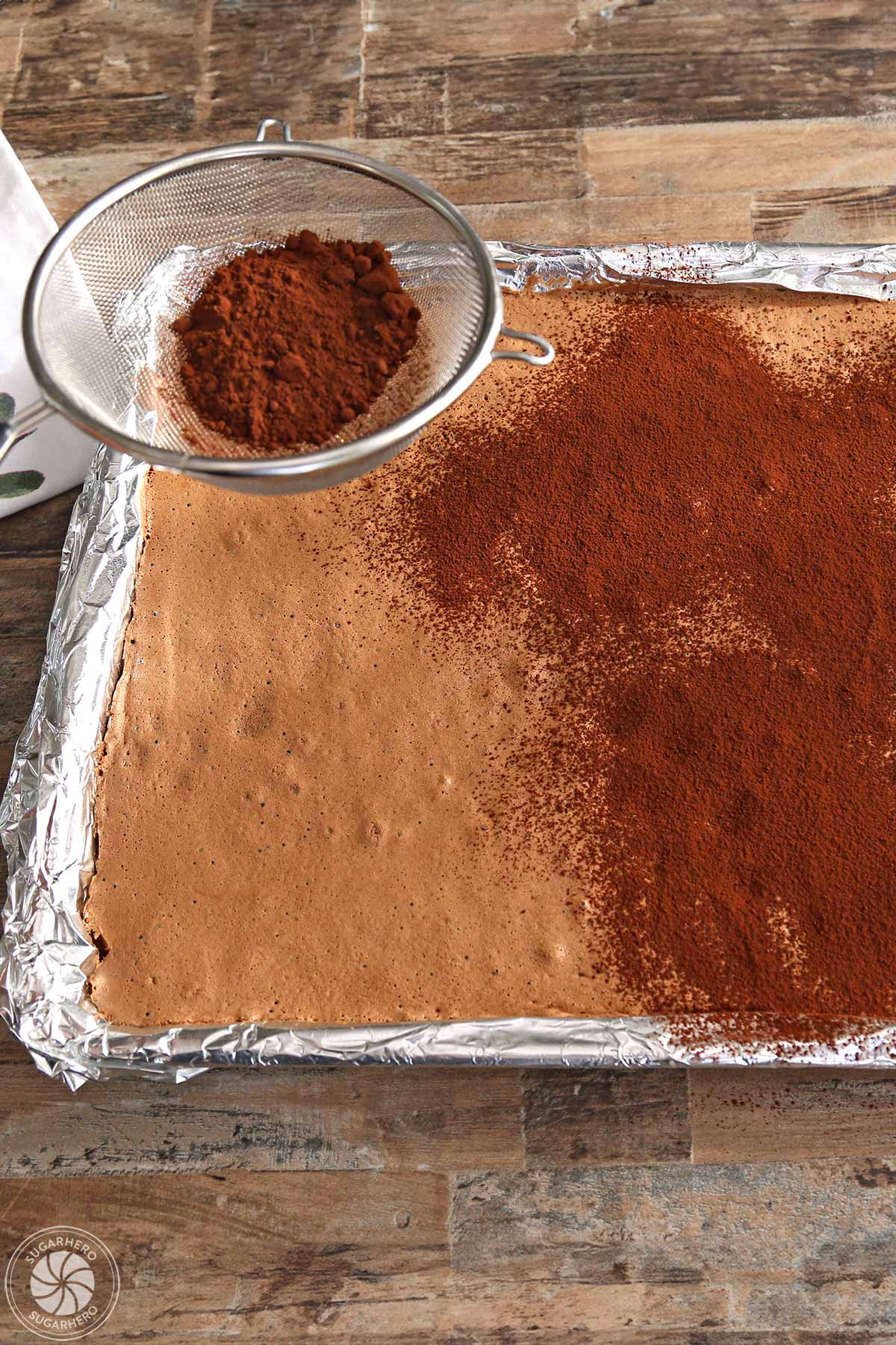 Sifting cocoa powder on top of the baked flourless chocolate cake.