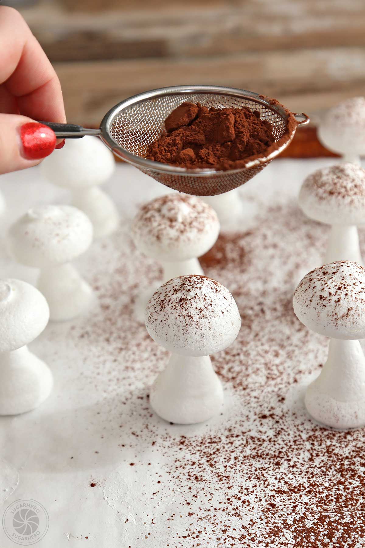 Sifting cocoa powder over meringue mushrooms.