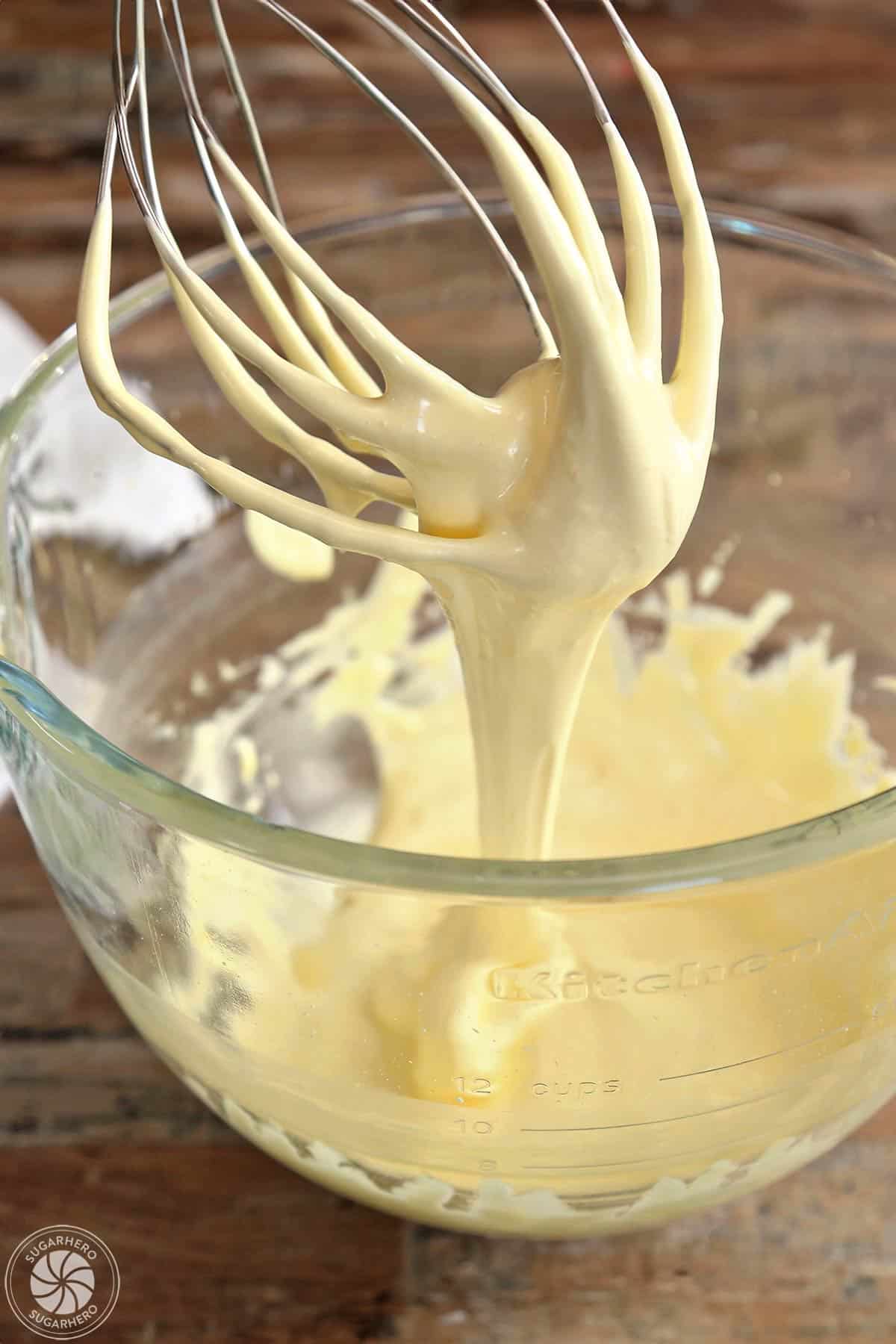 Mixed sugar and egg yolks on a whisk slowly falling back into the mixing bowl.