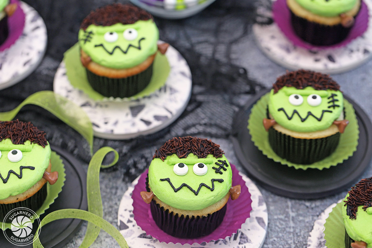 An assortment of Frankenstein Cupcakes on colorful wrappers.