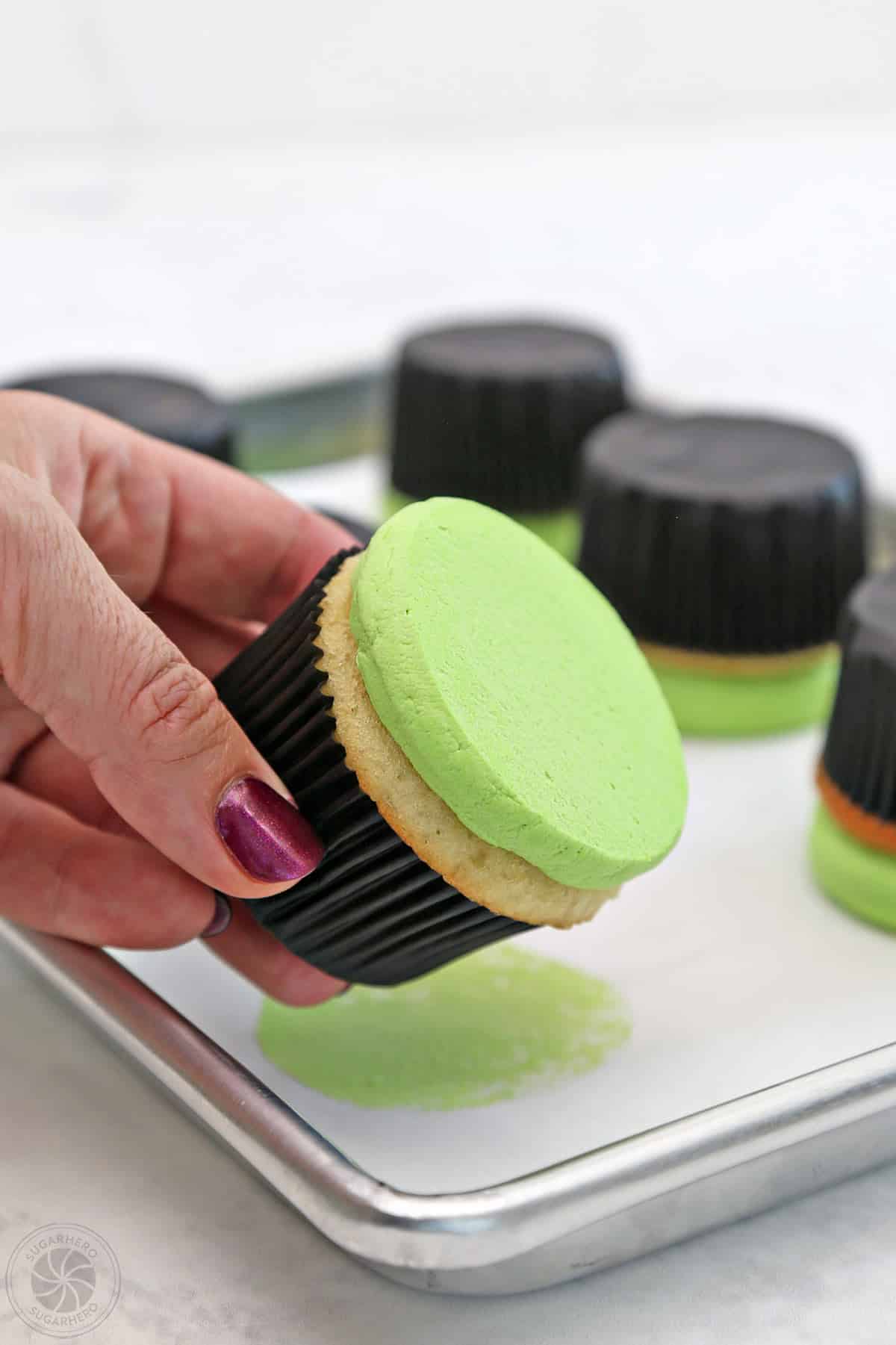 Hand displaying a cupcake with flattened green buttercream.