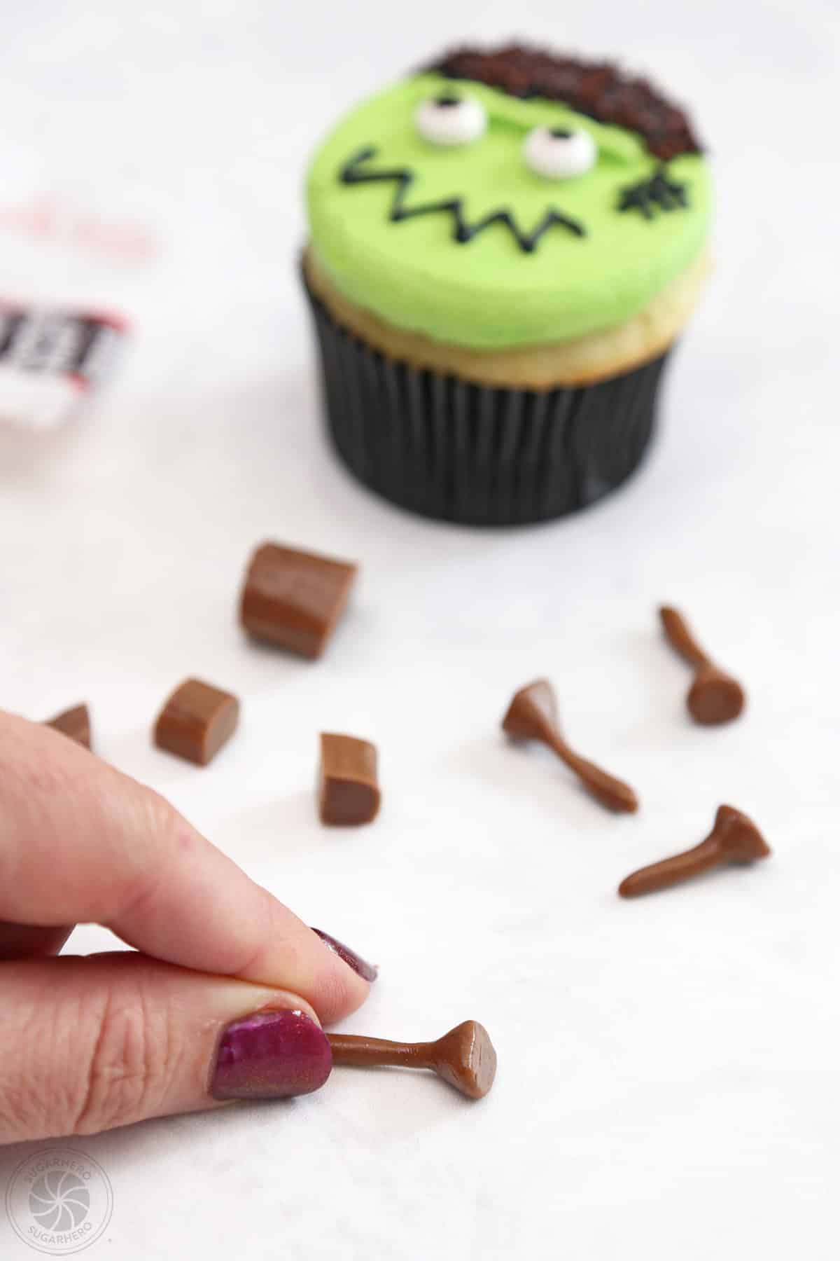 Hand modeling a tootsie rool to make neck bolts for Frankenstein Cupcakes.