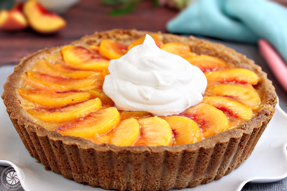 Close up of a Fresh Peach Tart with a large dollop of whipped cream on top.