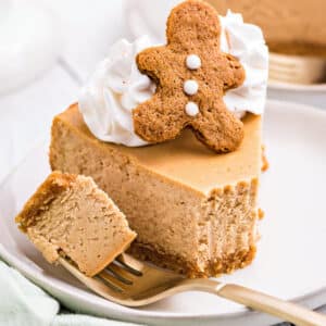Slice of Gingerbread Cheesecake on a white plate with a bite removed on a fork.